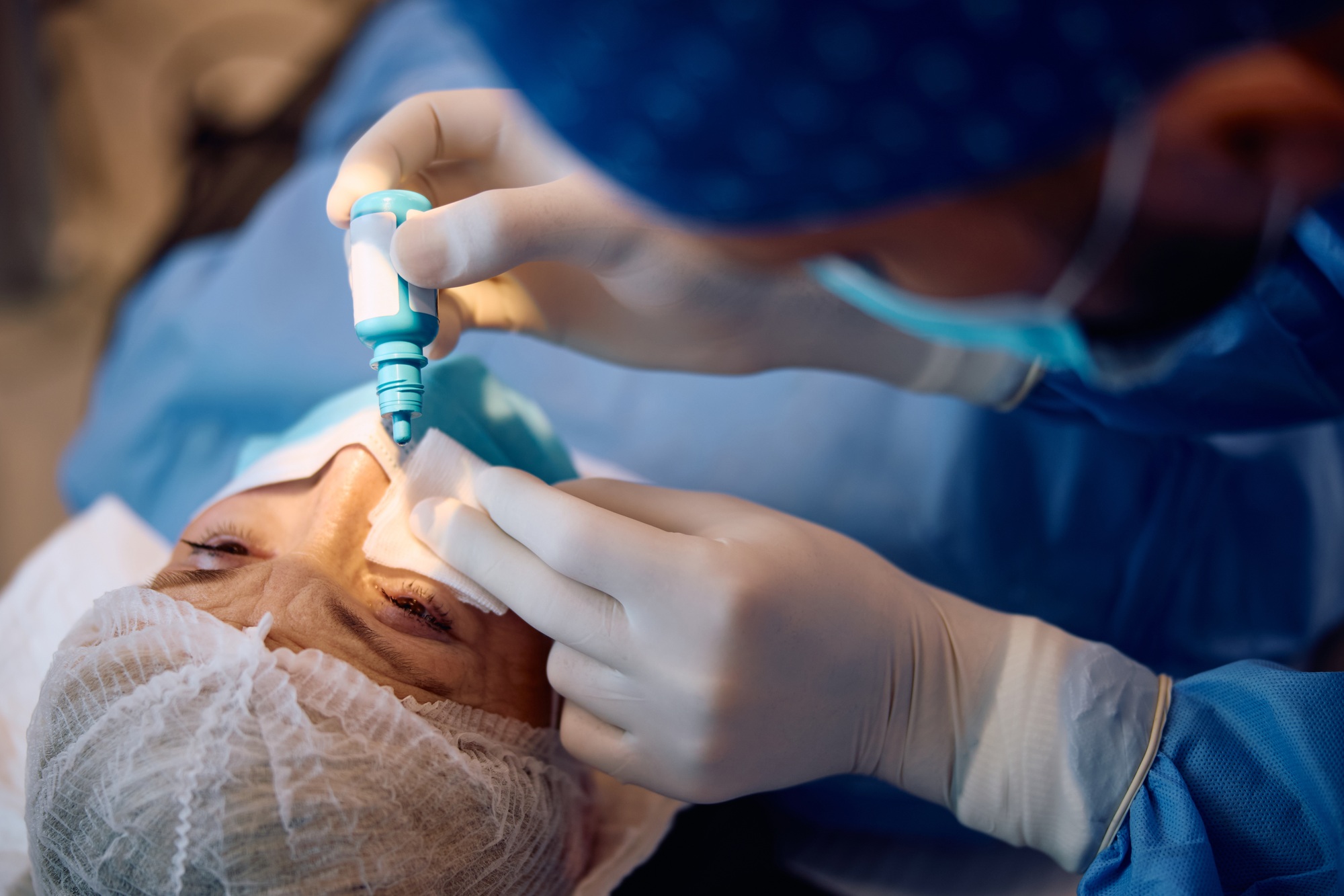Mature woman getting anesthetic eye drops before laser surgery at ophthalmology clinic.